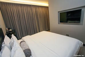 A hotel room with a bed, a TV mounted on the wall, and a curtain covering the window. - The Southbridge Hotel (Singapore)