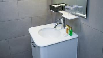A modern bathroom with a white sink, a mirror, and a shower.