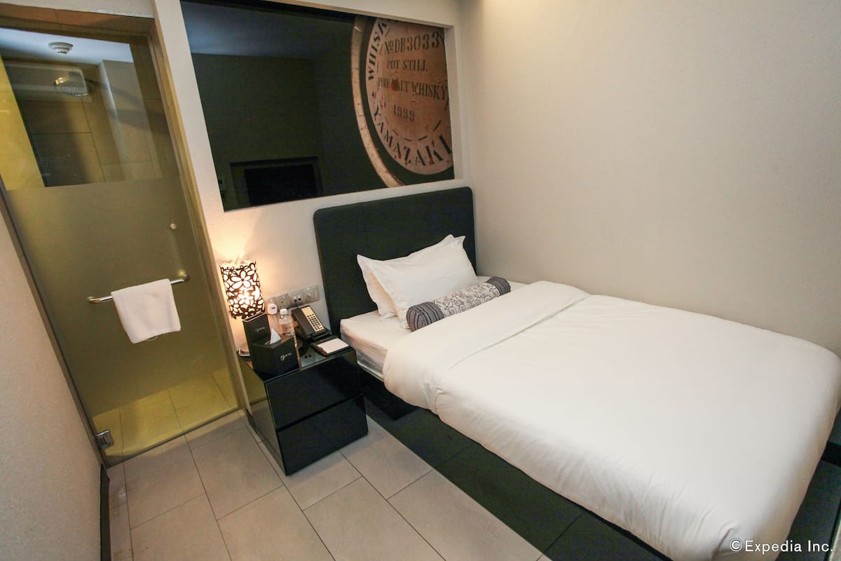 Una habitación de hotel con cama, mesita de noche, espejo y un cartel en la pared.