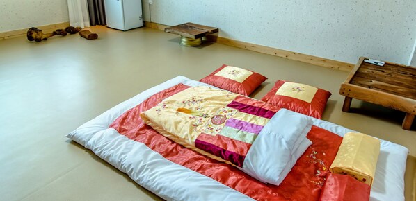 A traditional Japanese tatami mat room with a futon bed, pillows, and a small wooden table. - Badamaru Jeju (Seogwipo)