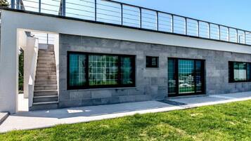 A modern building with a flat roof, large windows, and a staircase leading to an upper level.