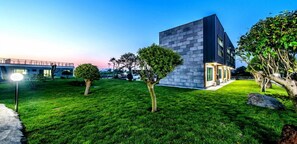 A modern building with a stone facade, surrounded by well-maintained grass and trees. - Badamaru Jeju (Seogwipo)