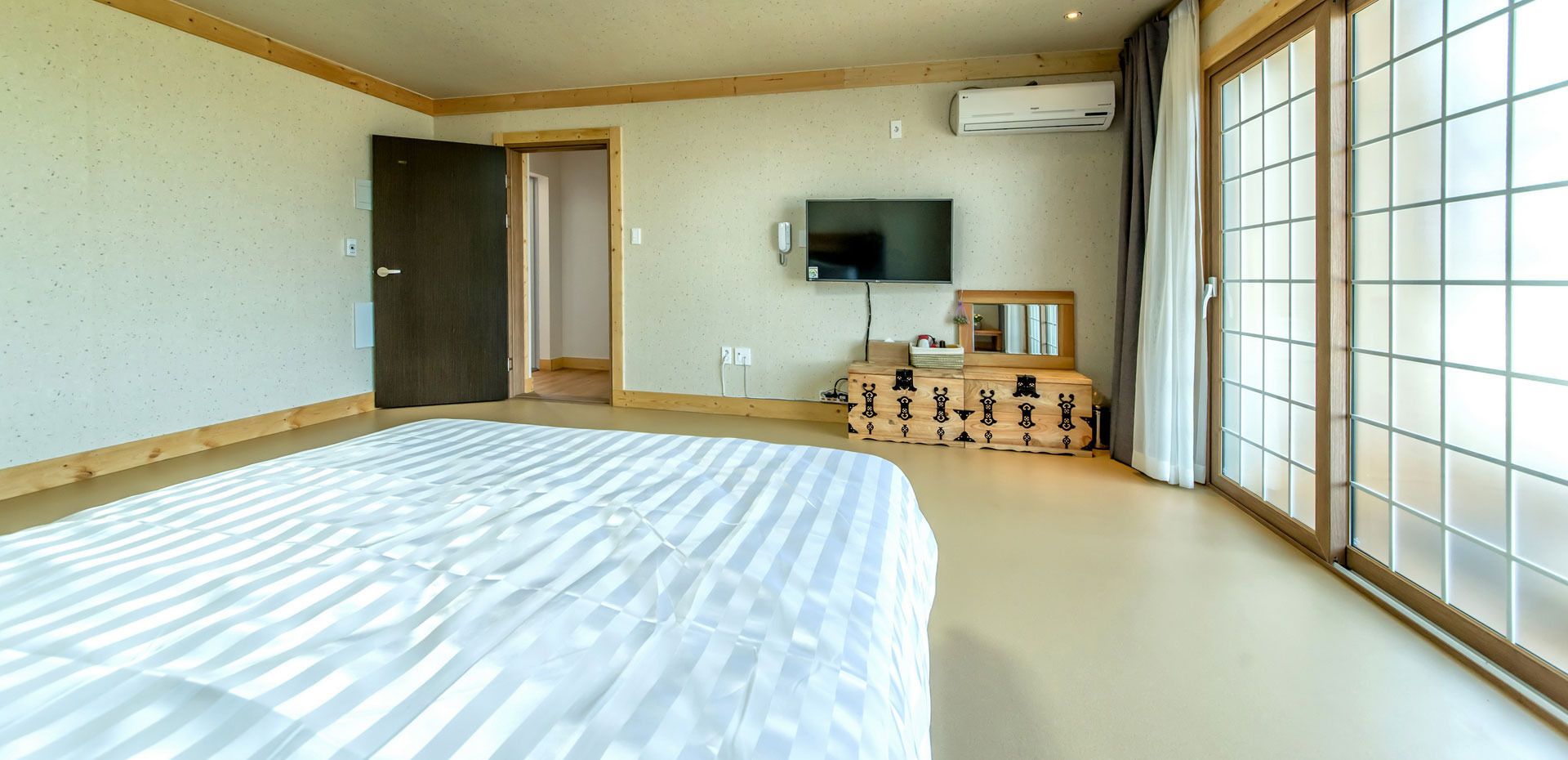 A bedroom with a large bed, a TV, and a dresser.