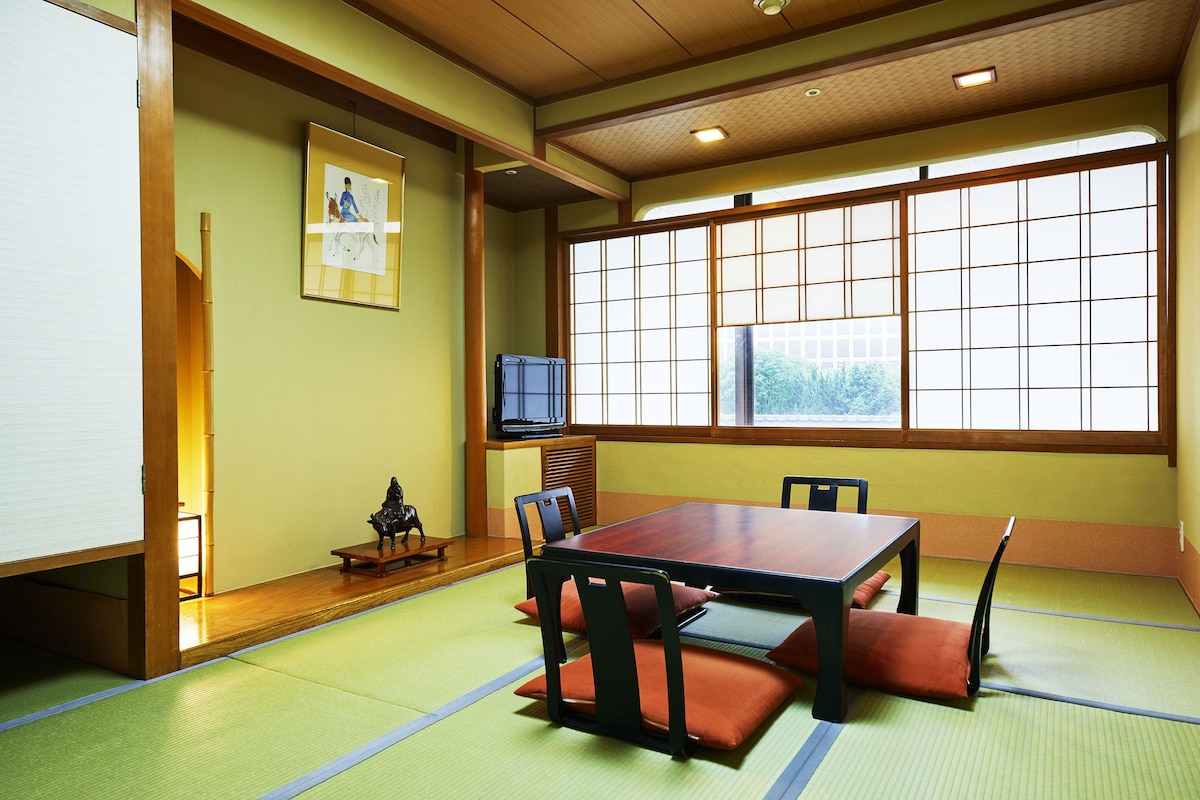 Una habitación japonesa tradicional con suelo de tatami, una mesa baja y sillas.