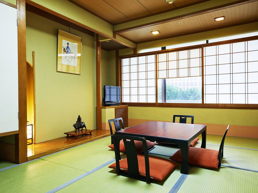 A traditional Japanese room with tatami flooring, a low table, and chairs.