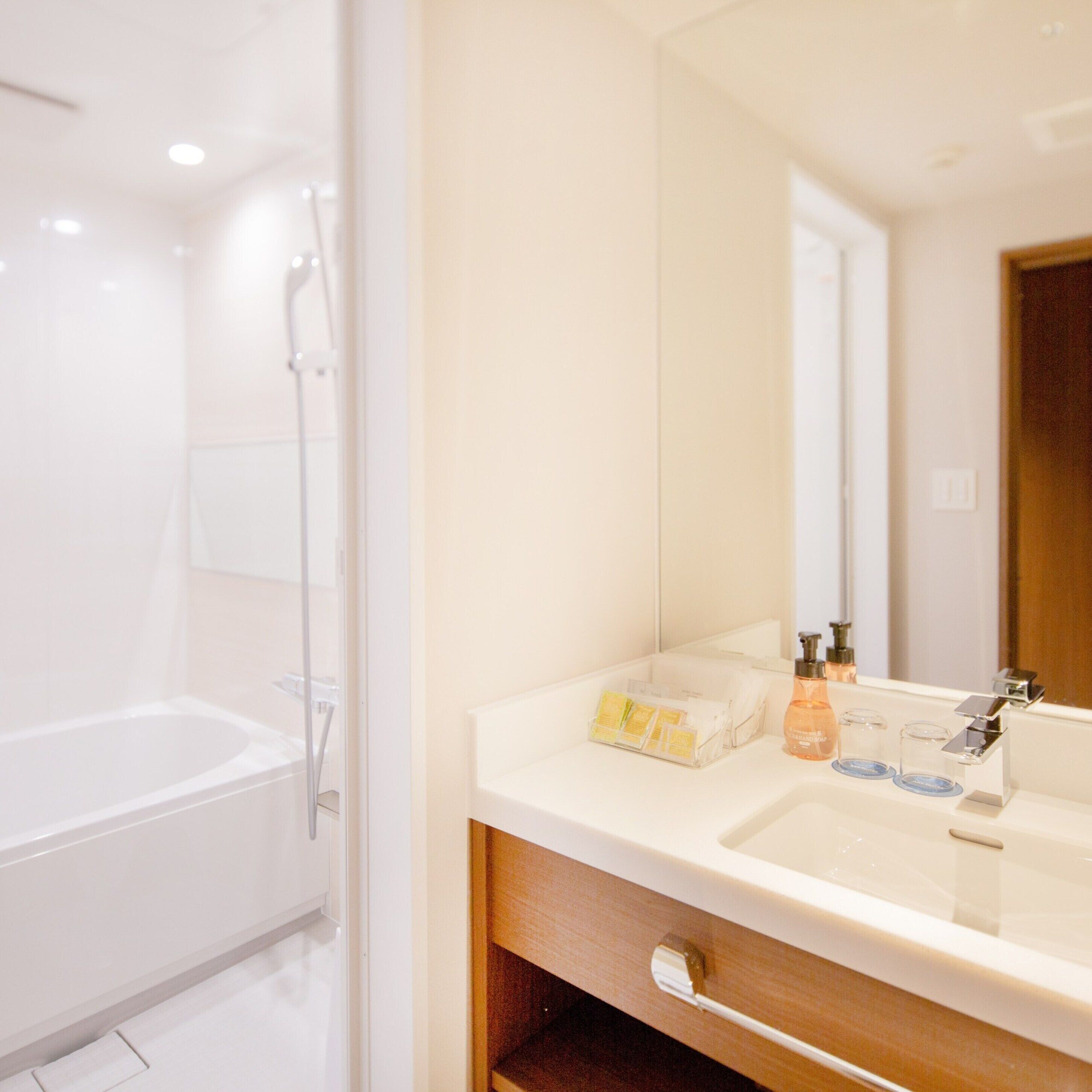 A modern bathroom with a white bathtub, a sink with a mirror, and toiletries.