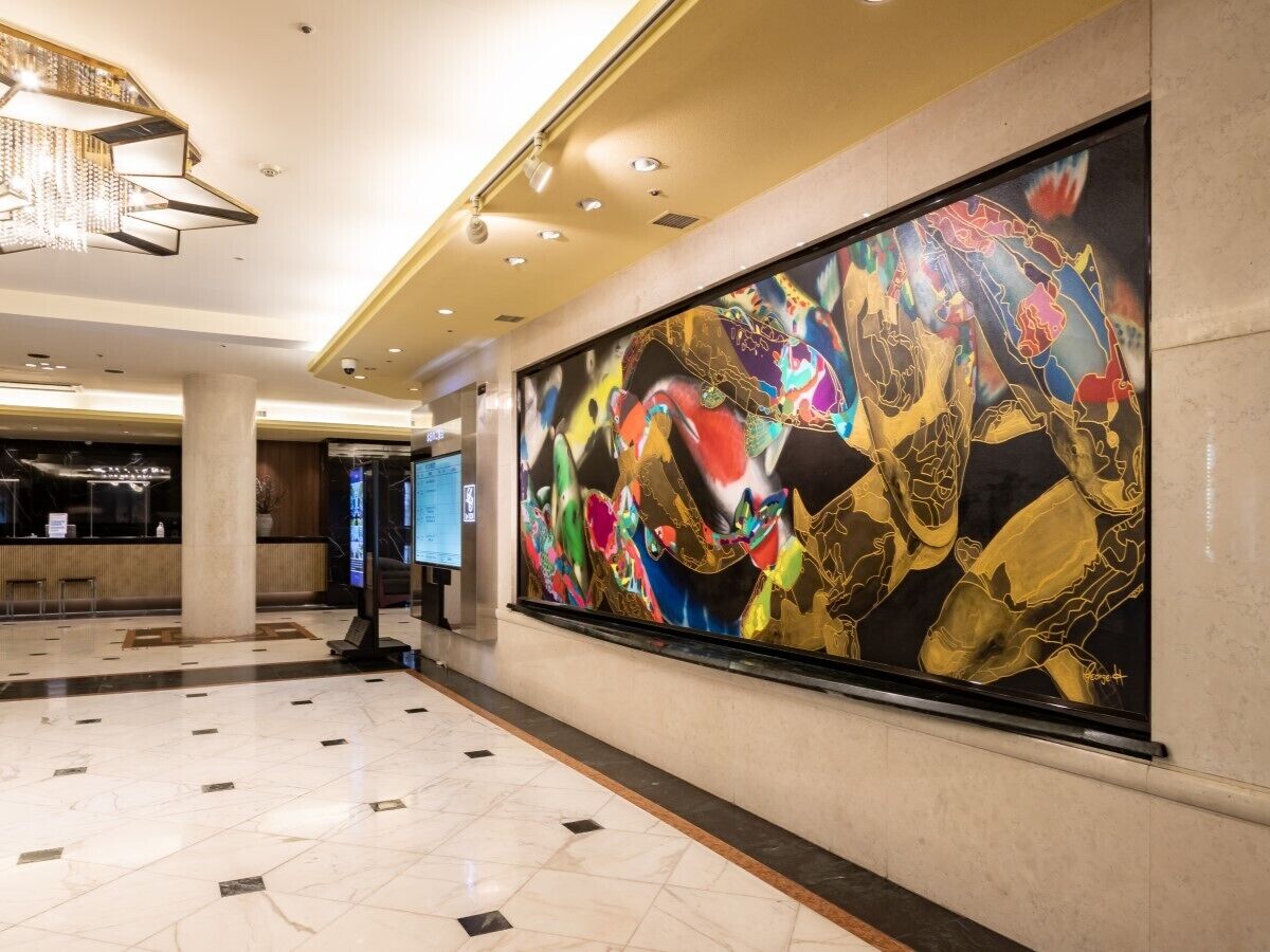 A spacious lobby with a large abstract painting, a reception desk, and a chandelier.