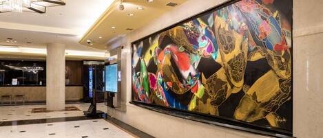 A spacious lobby with a large abstract painting, a reception desk, and a chandelier.