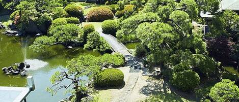 Ein traditioneller japanischer Garten mit einem Kiesweg, sorgfältig beschnittenen Büschen und einem kleinen Teich.