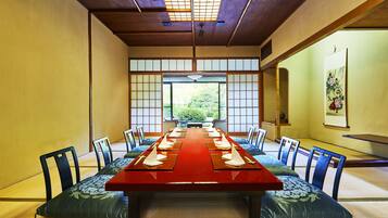 Ein traditioneller japanischer Besprechungsraum mit Tatami-Matten, einem langen Holztisch und niedrigen Holzstühlen.