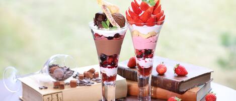 Two layered desserts on a table with books and scattered strawberries.