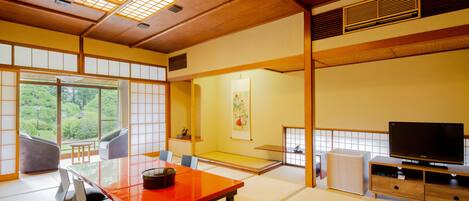 A traditional Japanese room with tatami flooring, a low table, and a television.
