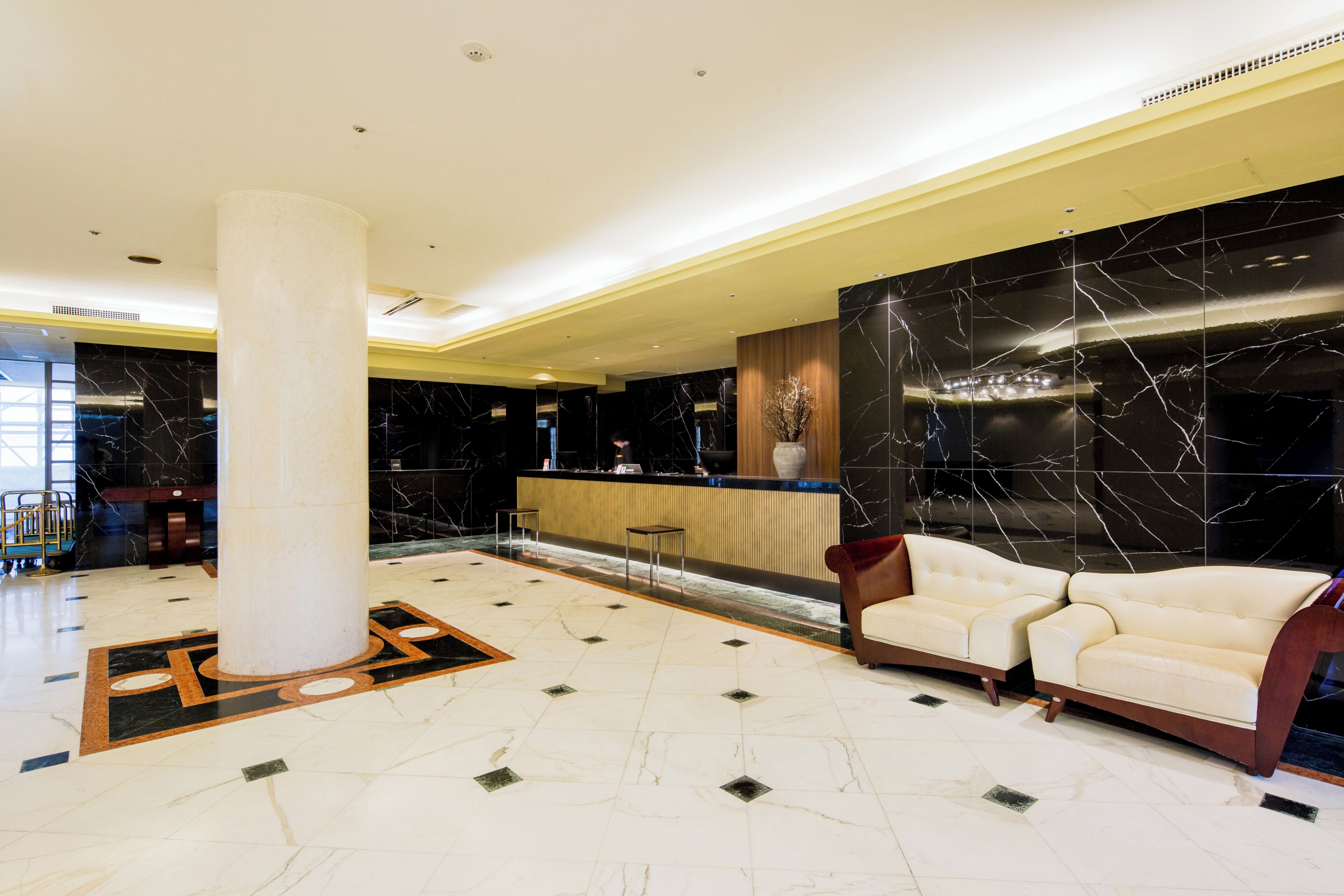 Una hall con reception, un’imponente colonna, un’area salotto e un pavimento in marmo.