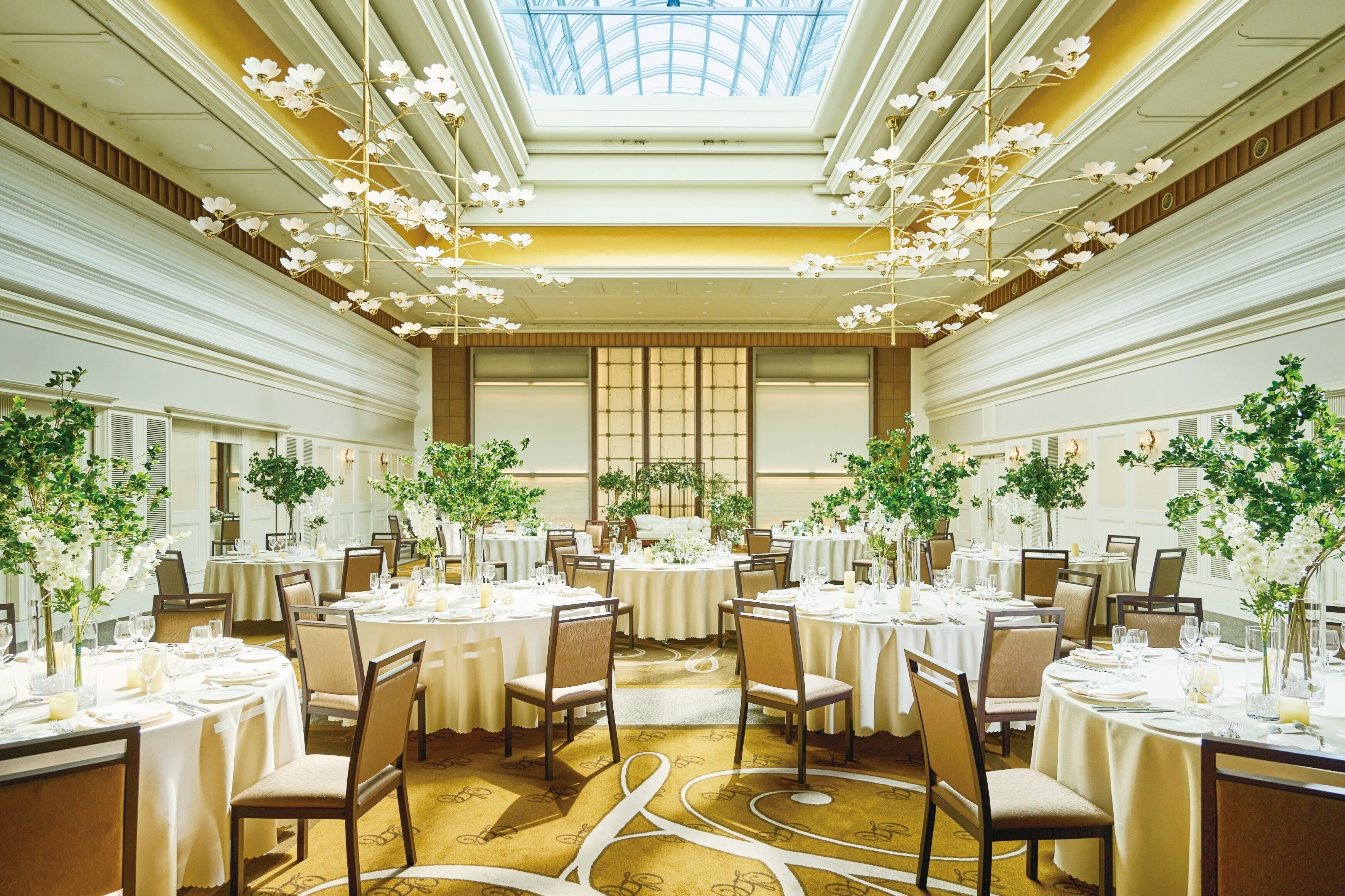 Ein Speisesaal eines Hotels mit runden Tischen, Stühlen und floralen Mittelpunkten.