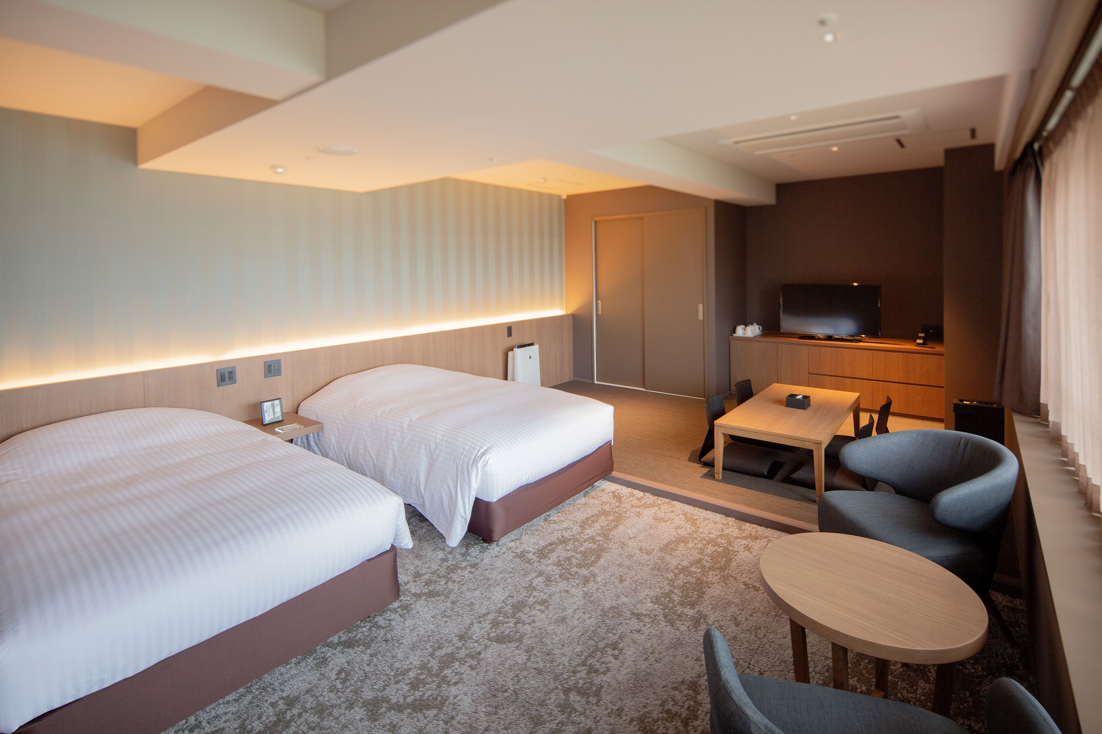 Habitación de hotel con dos camas, un escritorio, una silla, un televisor y un minibar.