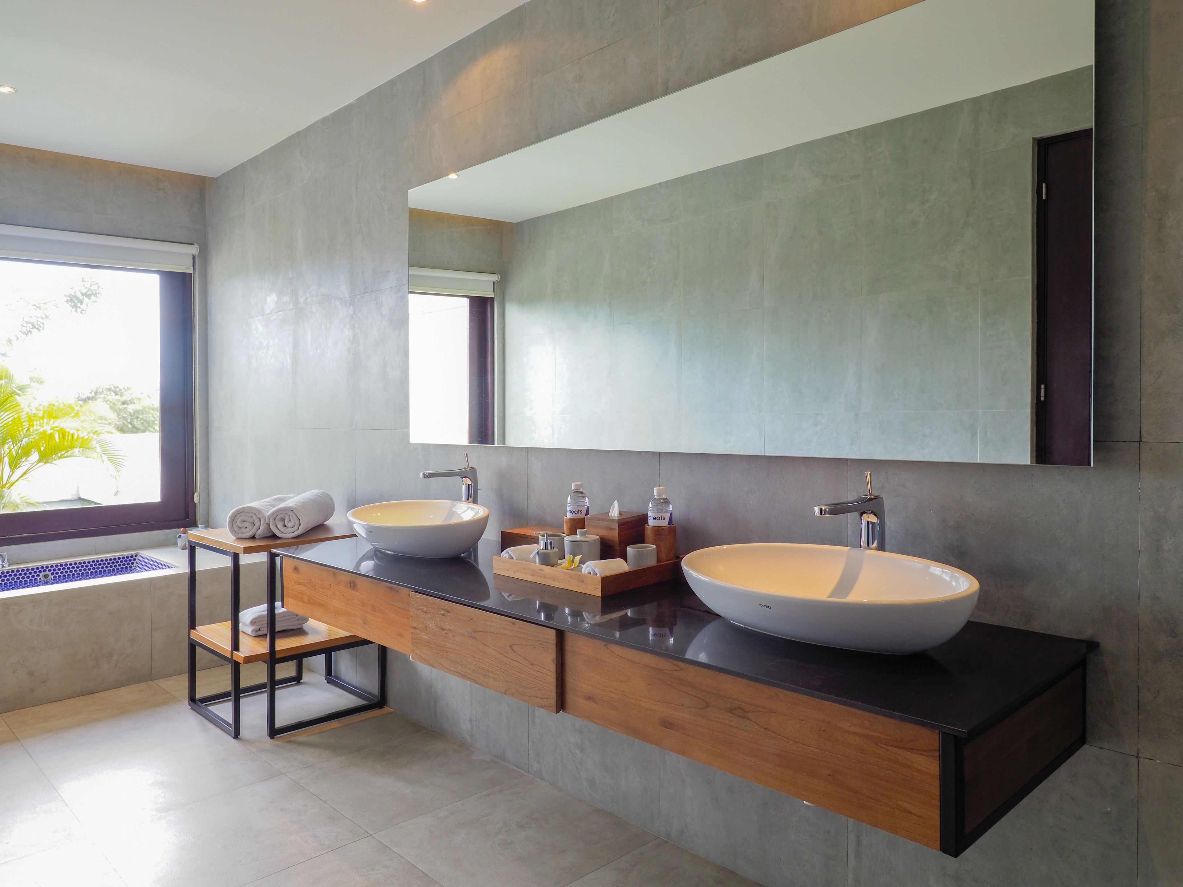 A modern bathroom with two large sinks, a large mirror, and a wooden vanity.