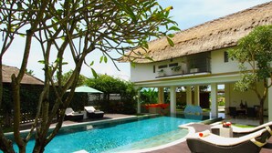 A pool area with lounge chairs, a thatched-roof building, and a wooden deck. - The Samata by LifestyleRetreats (Denpasar)