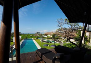 A poolside area with lounge chairs and a view of a landscaped garden and pool.