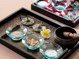 A tray with various items including bowls of powders, a flower, and a traditional wooden mortar and pestle.