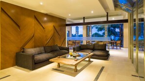 Un salon moderne avec deux canapés, une table basse en verre et un mur décoratif en bois.