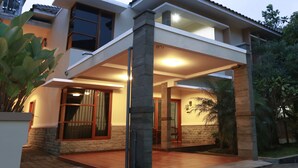 A modern two-story house with a covered patio, large windows, and a stone facade. - Kuldesak Villas (Bandung)