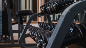A gym with weightlifting equipment, including dumbbells and benches. - Kuldesak Villas (Bandung)