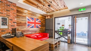A reception area with a wooden desk, red sofa, and a large British flag. - Warehouse Inn (Hengchun)