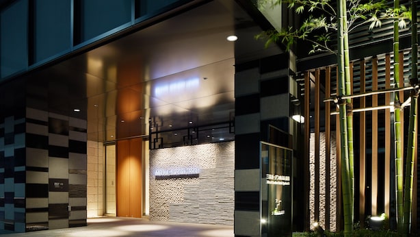 The exterior of Mitsui Garden Hotel with a modern design, featuring a stone wall and bamboo plants. - Mitsui Garden Hotel Kyobashi Tokyo Station (Tokyo)