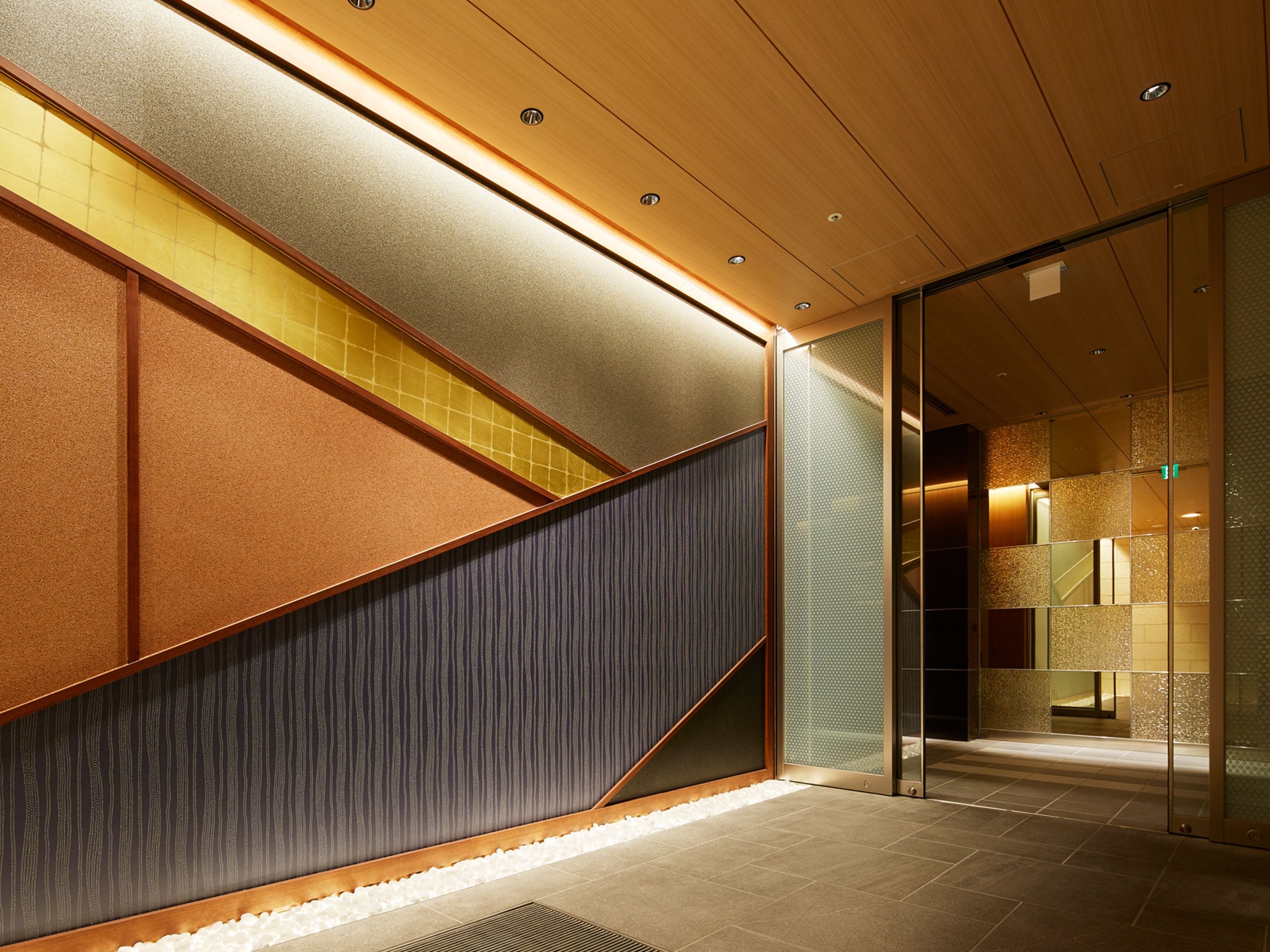 Ein modernes Interieur mit einer Holztreppe, strukturierten Wänden und einer Glastür zu einem weiteren Raum.