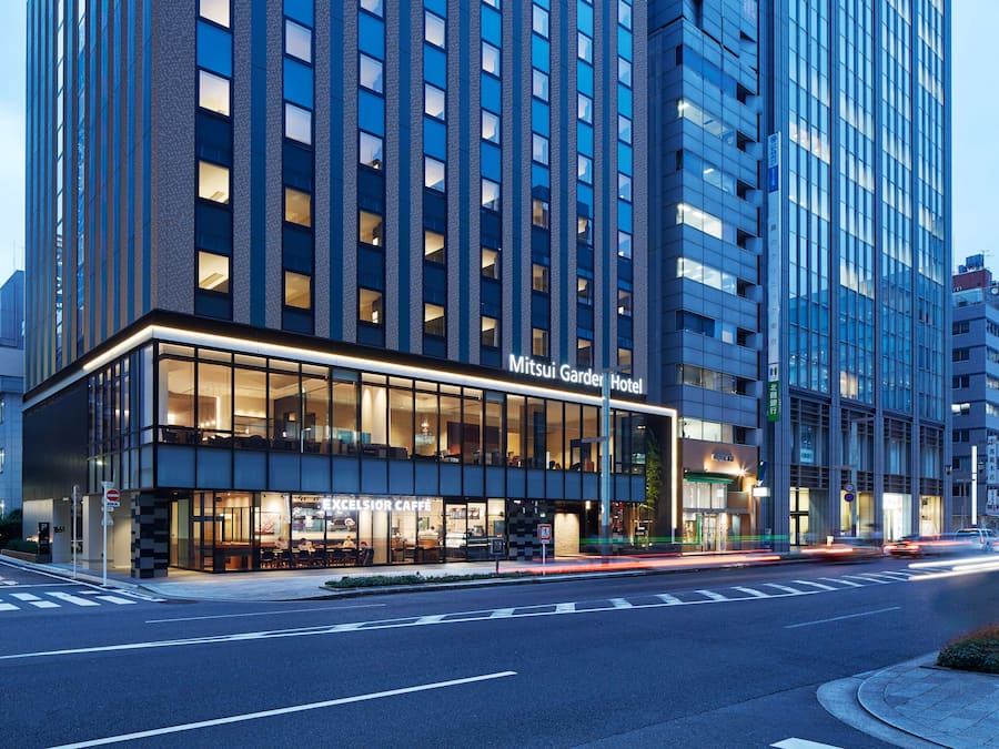 Un hotel moderno con fachada de vidrio, señalización que dice "Mitsui Garden Hotel" y una entrada visible.