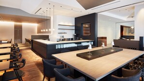 A modern restaurant with a central island, seating around it, and a bar area. - Mitsui Garden Hotel Kyobashi Tokyo Station (Tokyo)