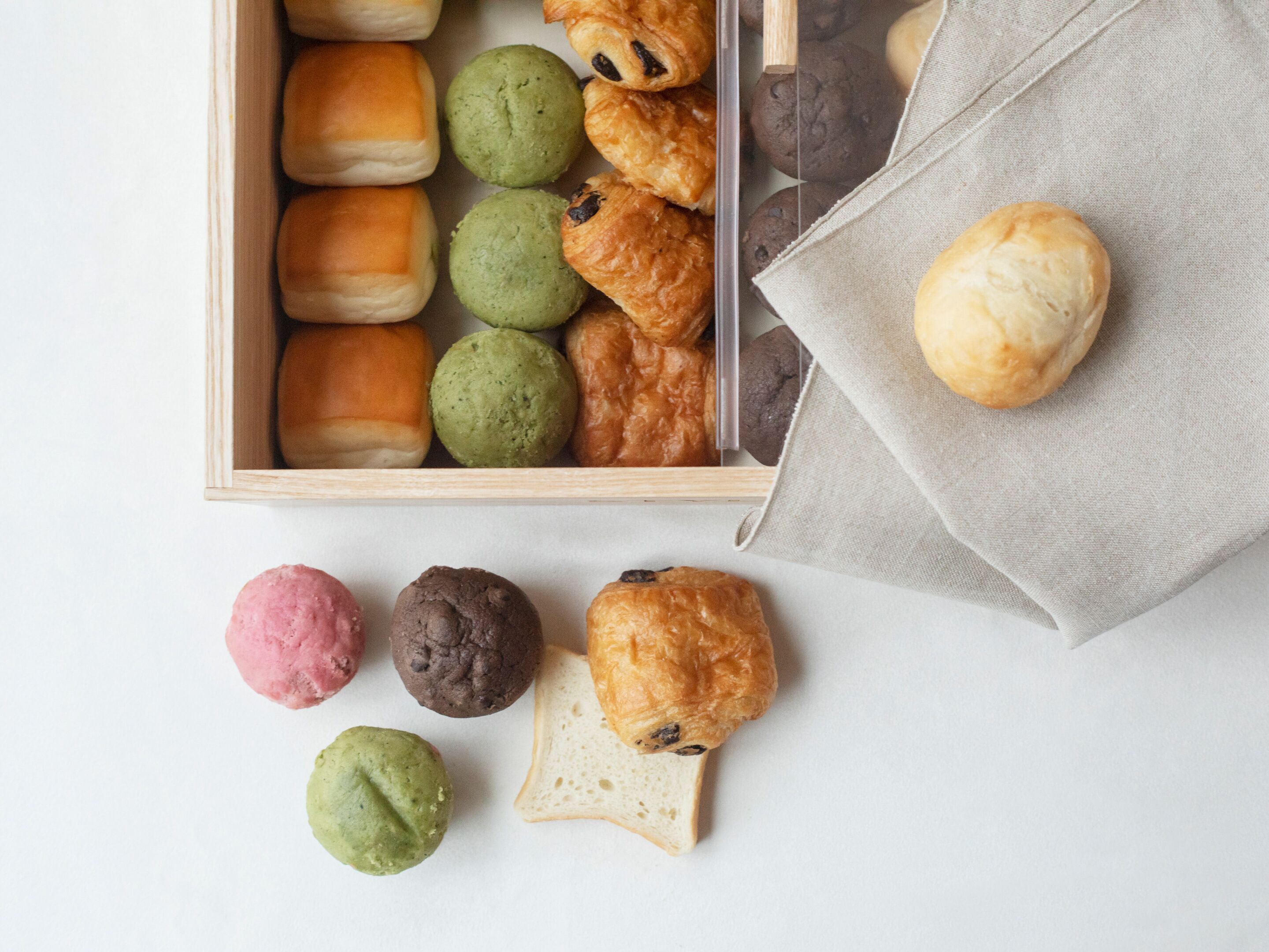 A variety of pastries in a wooden box and on a napkin.