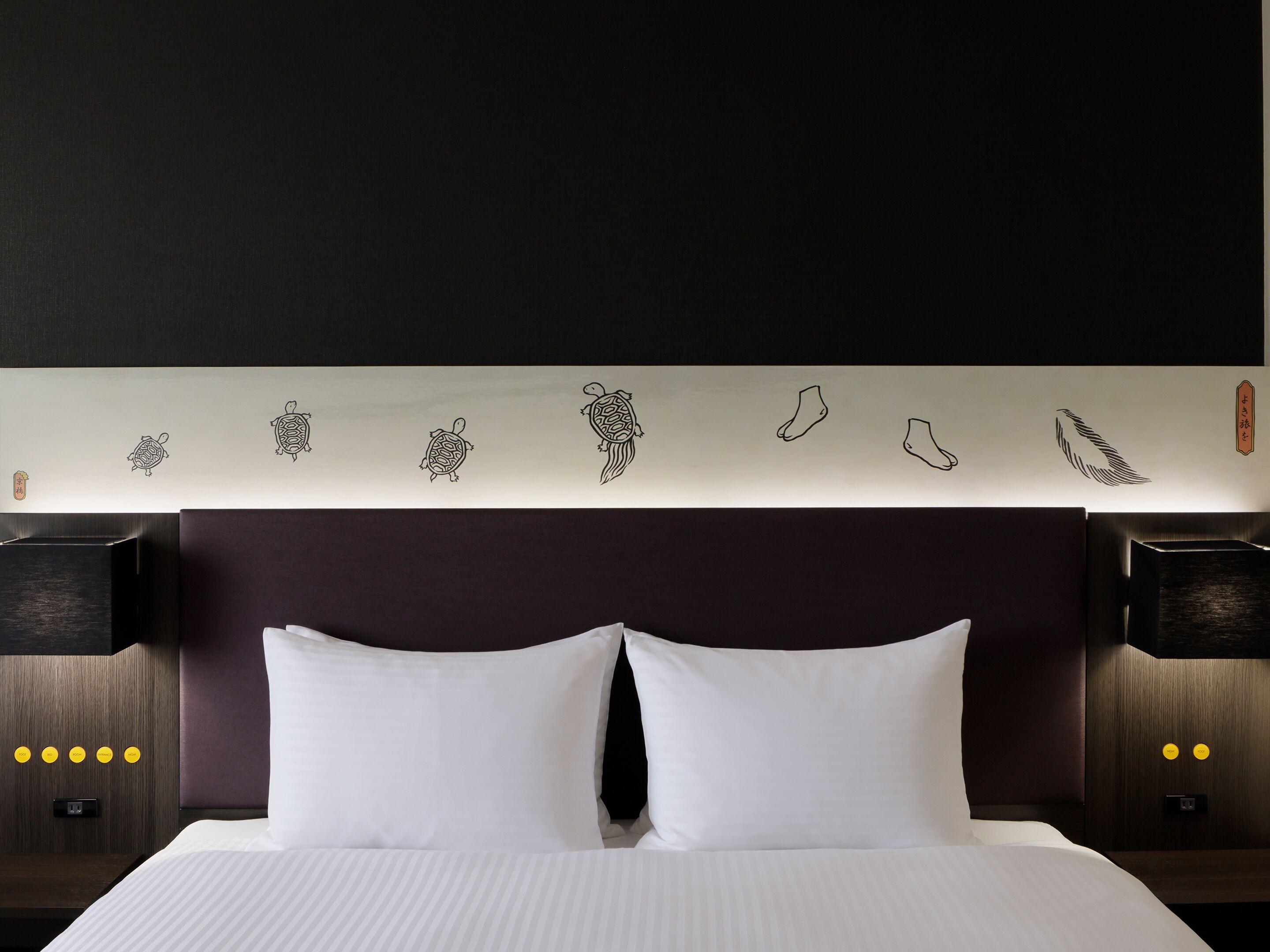 A hotel room with a large bed, two bedside tables, and a wall with decorative wall art.