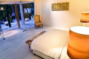 A bedroom with a bed, a chair, a lamp, and a painting on the wall. - Villa Greenday (Cepaka)