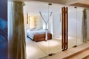 A modern bedroom with a glass partition, a bed, and a wicker chest of drawers. - Villa Greenday (Cepaka)