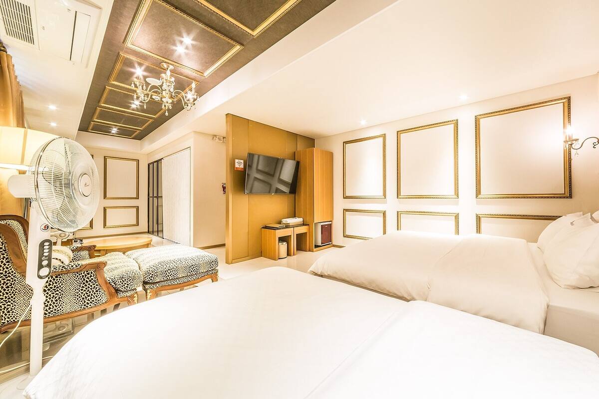 Habitación de hotel con una cama grande, un escritorio con silla, televisor y minibar.