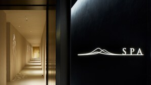 Interior de un spa moderno con un largo pasillo que conduce a un área de spa, un logotipo minimalista en la pared y un suelo con diseño.