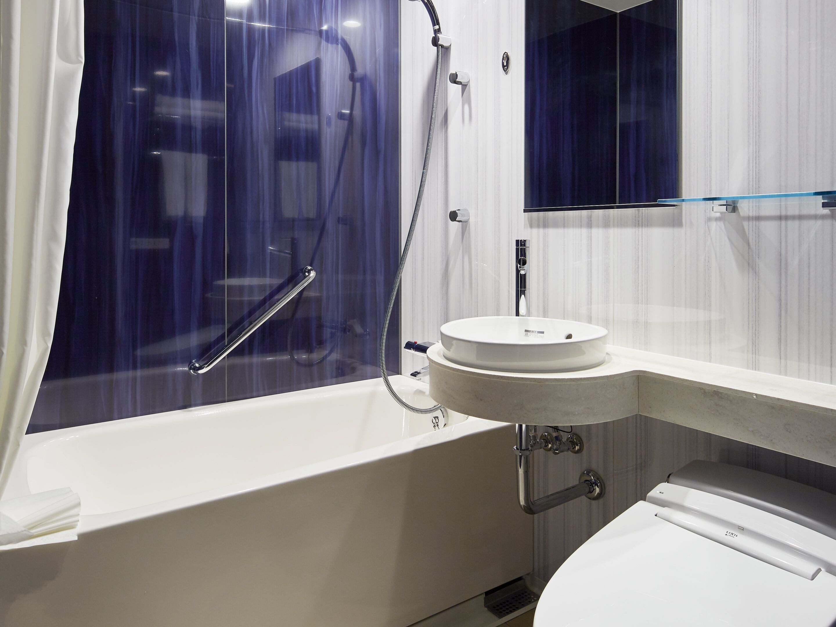 Een moderne badkamer met een badkuip, een rond wastafel en een toilet.