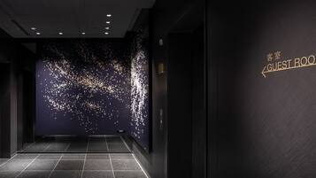A modern hotel lobby with a dark floor, a wall with a 'Guest Room' sign, and a ceiling with recessed lighting.