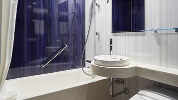A modern bathroom with a bathtub, a round sink, and a glass shower enclosure.