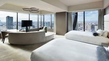 A modern hotel room with a curved seating area, a large bed, and a city view.