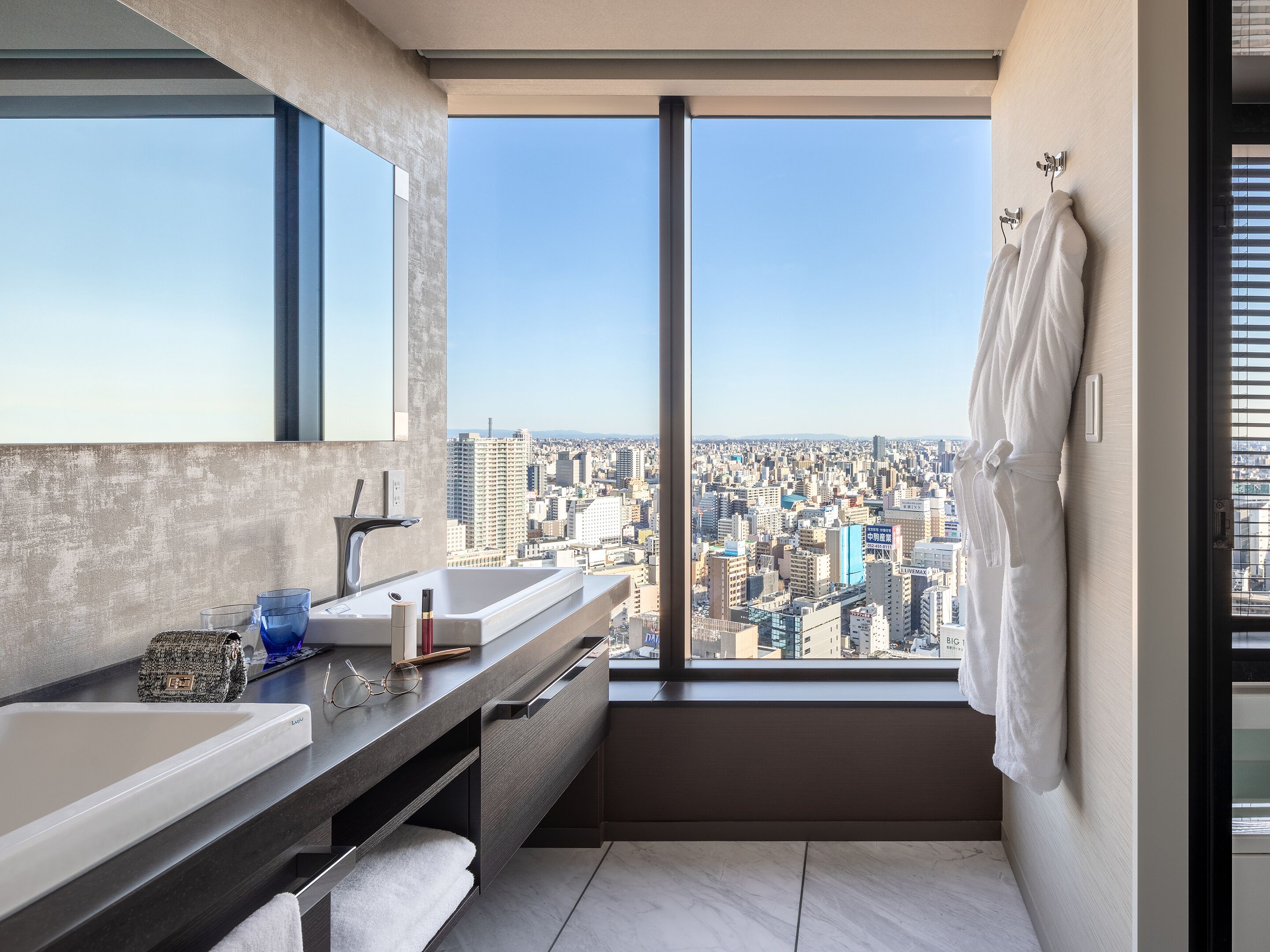 A modern bathroom with a large window, a sink, and a mirror.