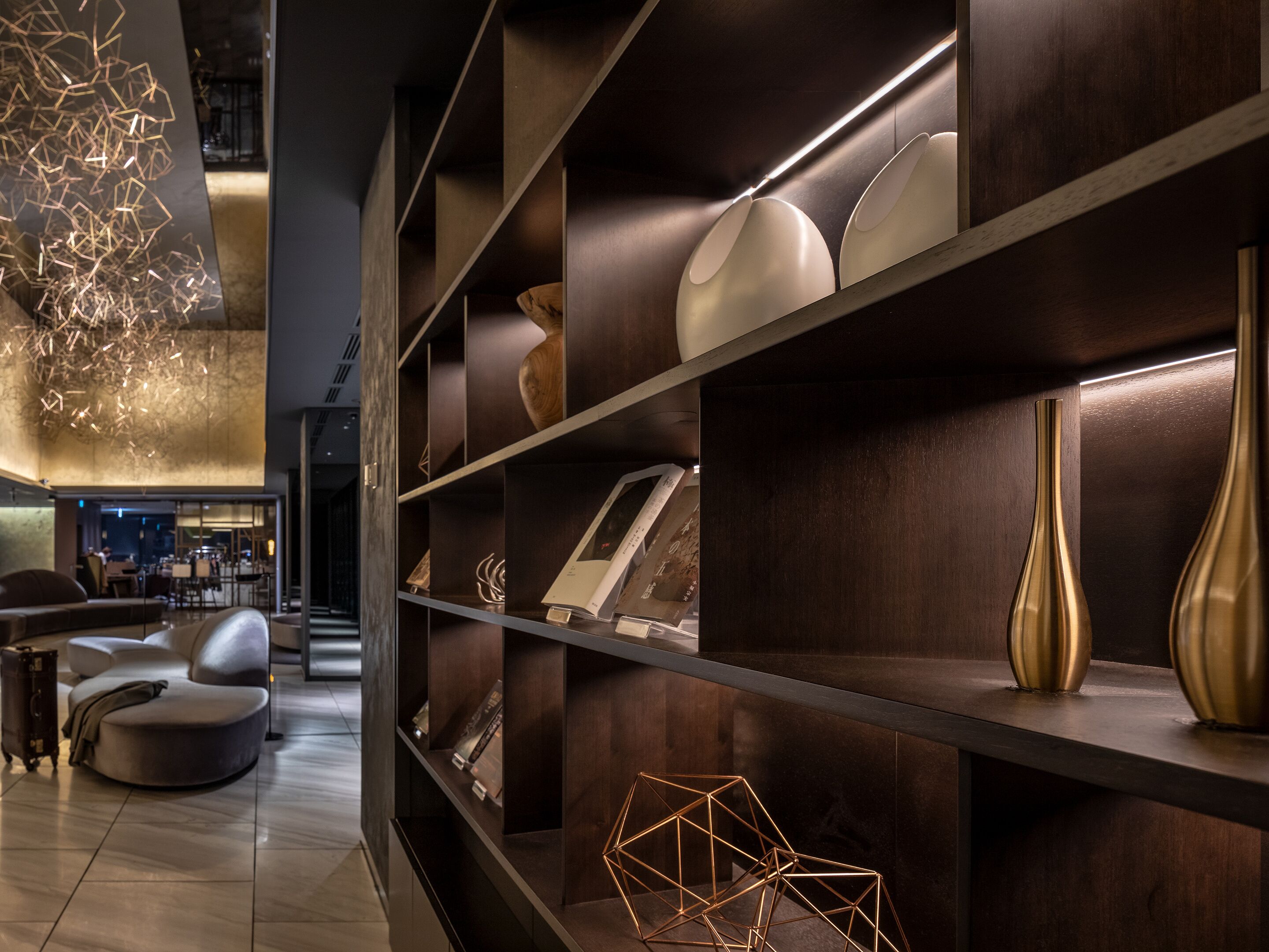 A modern interior with dark wood shelving displaying various decorative items and a seating area with a sofa and chairs.