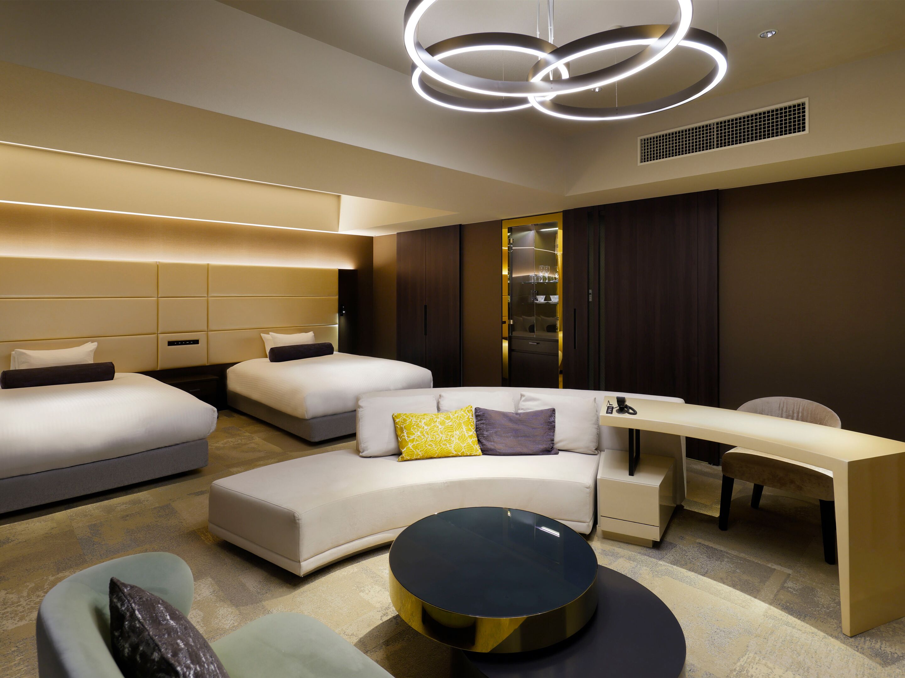A modern hotel room with a large bed, a sofa, a desk, and a round coffee table.