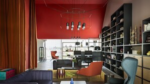 A modern living room with a red accent wall, a black bookshelf, and contemporary furniture. - OKKO Hotels Bayonne Centre (Bayonne)