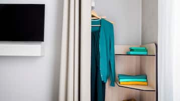 Una camera da letto con un letto, un armadio, uno scaffale con vestiti piegati e un paio di scarpe.