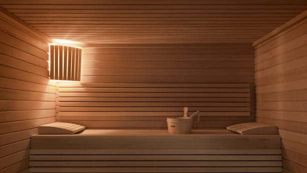 A sauna with wooden walls, benches, and a bucket with a ladle. - OKKO Hotels Bayonne Centre (Bayonne)