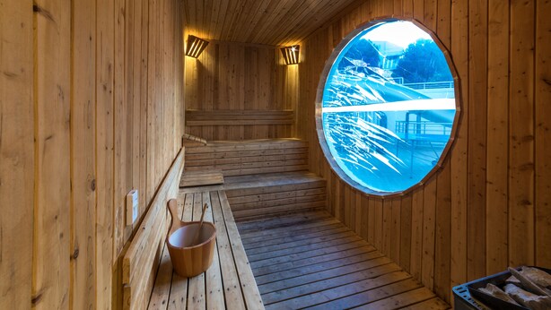 A wooden sauna with a circular window, wooden steps, and a bench with a bucket. - Piccolo Dream Hotel - All Inclusive - Adults Only (Marmaris)