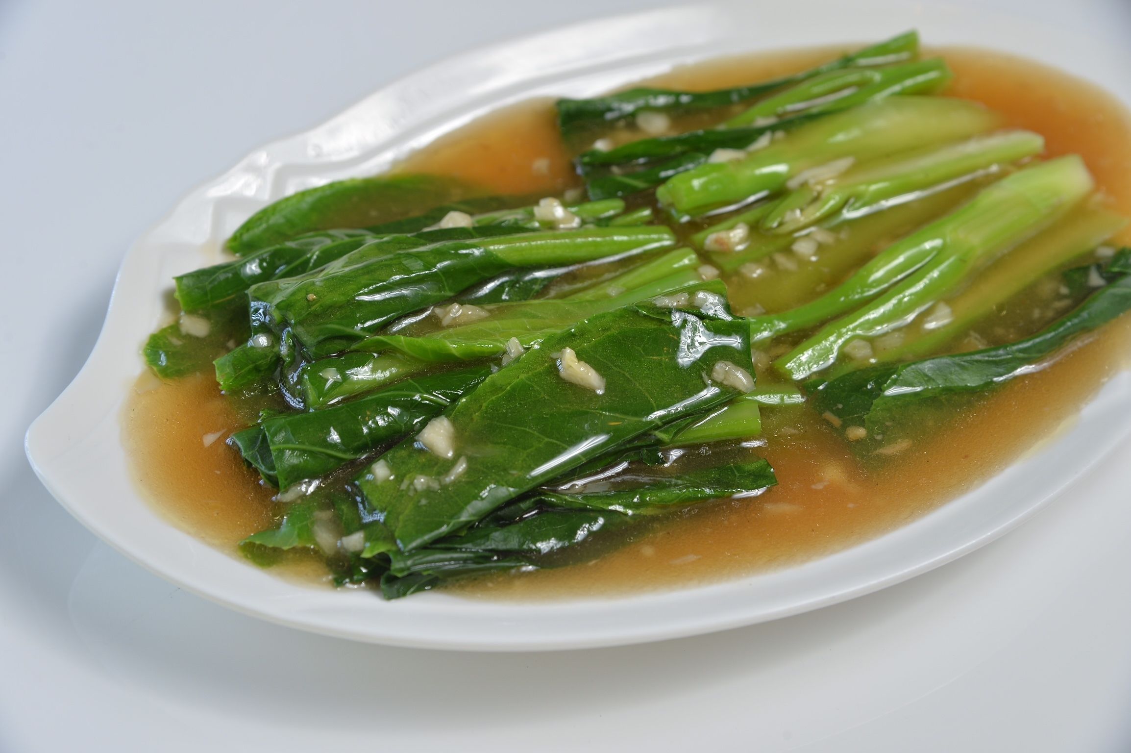 A dish of bok choy in a clear broth.