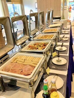 A buffet setup with multiple self-service stations, including trays of sliced meats, vegetables, and other prepared foods. - Holly Hotel Myanmar (Yangon)